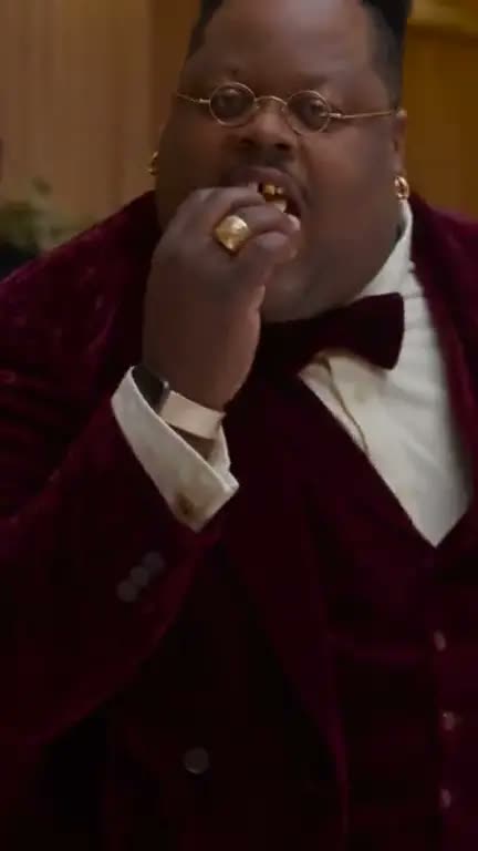 A man in a velvet suit bites into a concha: an AI version posted on TikTok by @montgomery.baptiste